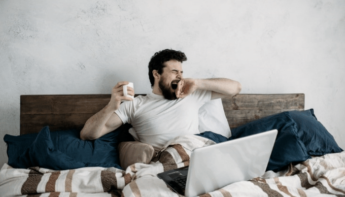 Gentleman Laying In Bed Yawning And Drinking Coffee