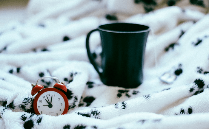 Coffee Cup And Alarm Clock On A Blanket