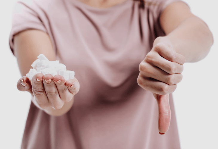 Cropped closeup of woman holding unhealthy white sugar with thumb down