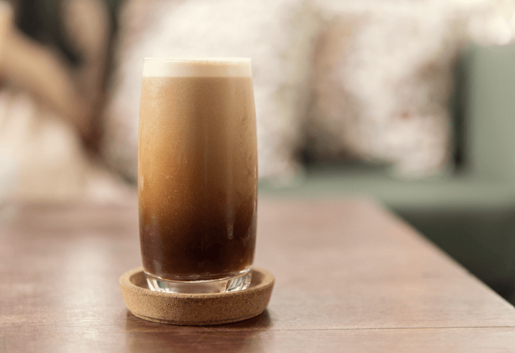 Nitro coffee drink in a glass foaming with bubbles