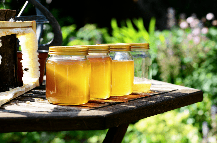 Honey jars on a table near a beehive in the garden