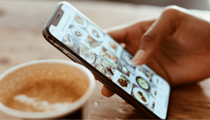 Hand with iPhone ordering in coffee shop 