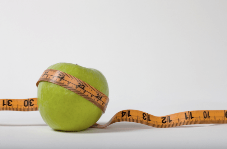 An apple and tape measure, illustrating that skin health and coffee 