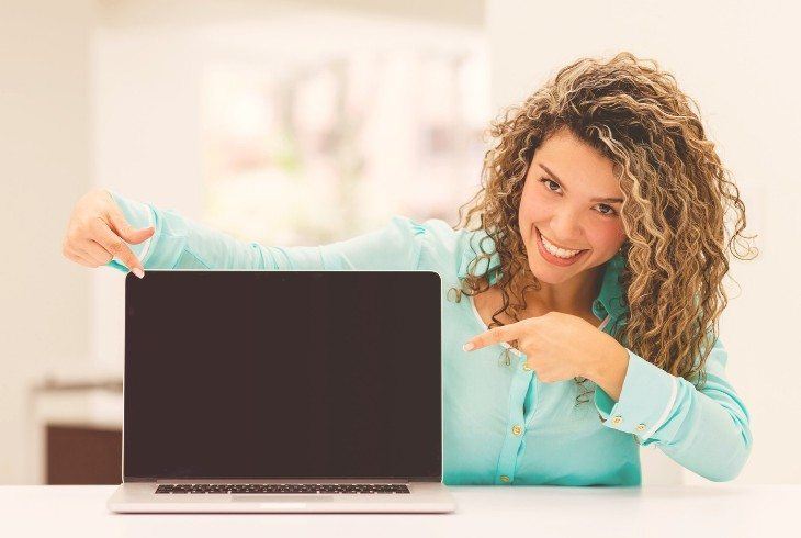 Young woman pointing at a laptop to encourage getting on line