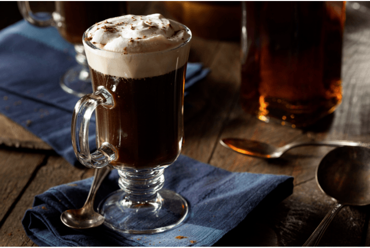 Irish coffee on a blue napkin with a bottle of whiskey