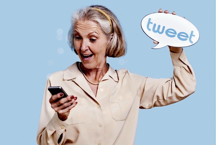 Woman tweeting on her phone holding a sign that says tweet