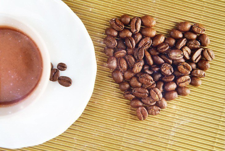 Coffee bean heart next to a cup illustrating the health benefits of coffee