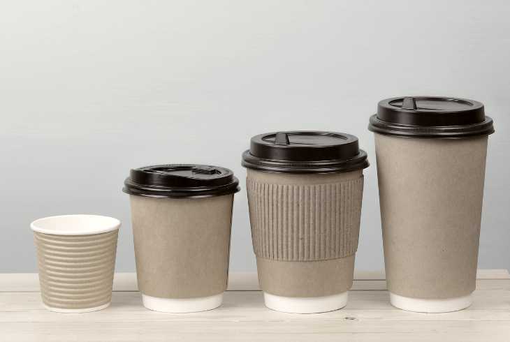 Four paper coffee cups with blue background