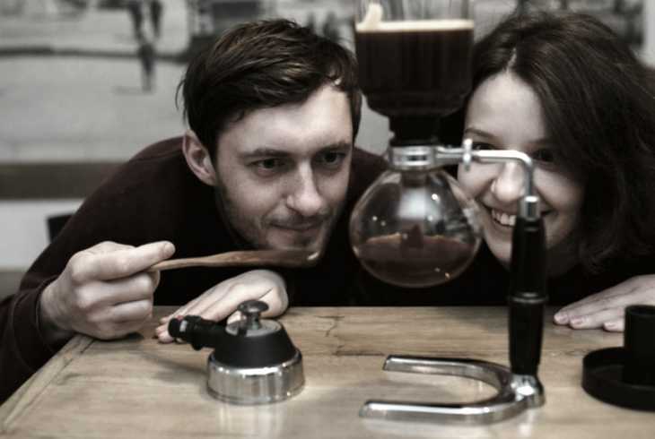 Young couple watching a siphon coffee maker work