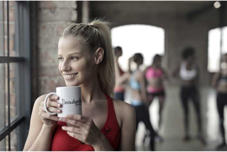 Young woman drinking coffee before workout