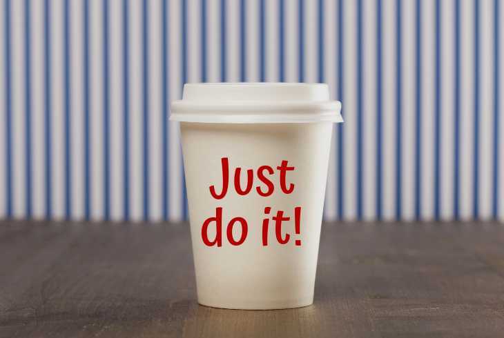 "Just dot it" on a coffee cup sitting on a table