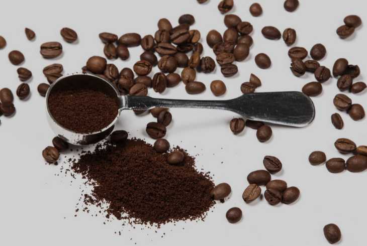 Coffee scoop, beans, ground coffee on a grey background