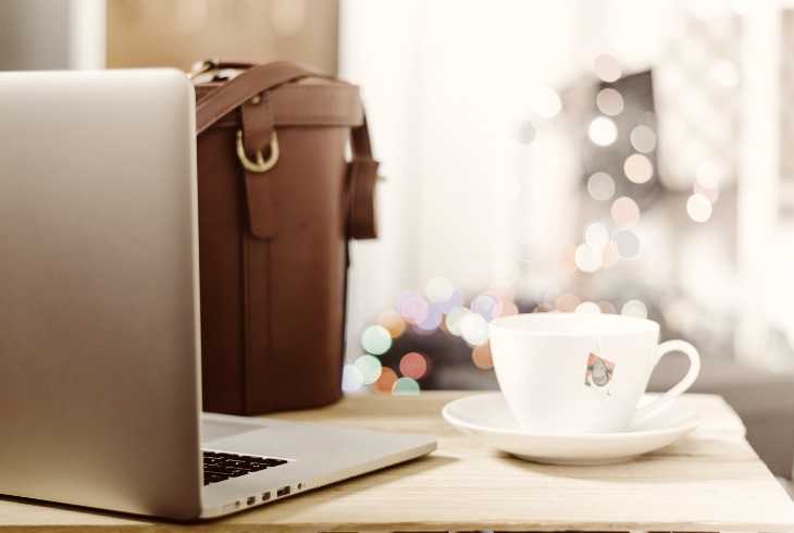 Laptop, briefcase and favorite coffee cup on employee desk