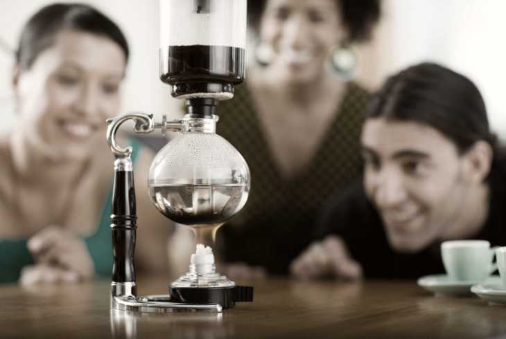 Three friends watching a vacuum coffee maker